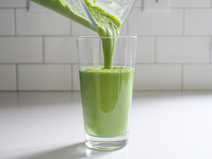 Pouring the matcha green tea Frappuccino into a 20 ounce clear glass.