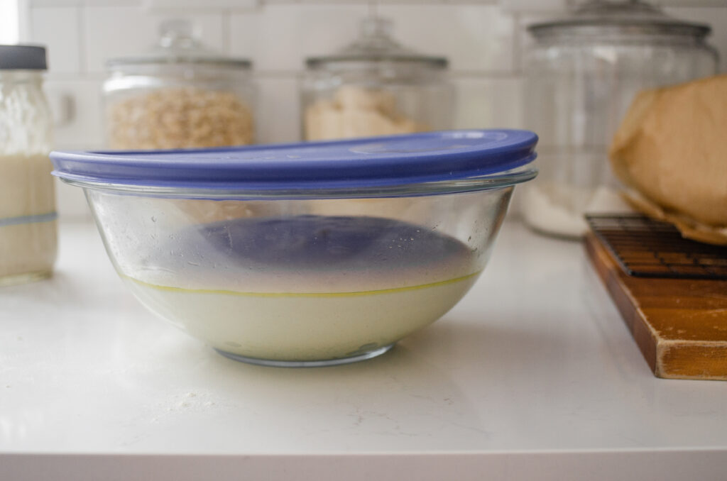 A large glass mixing bowl with sourdough bread dough inside.