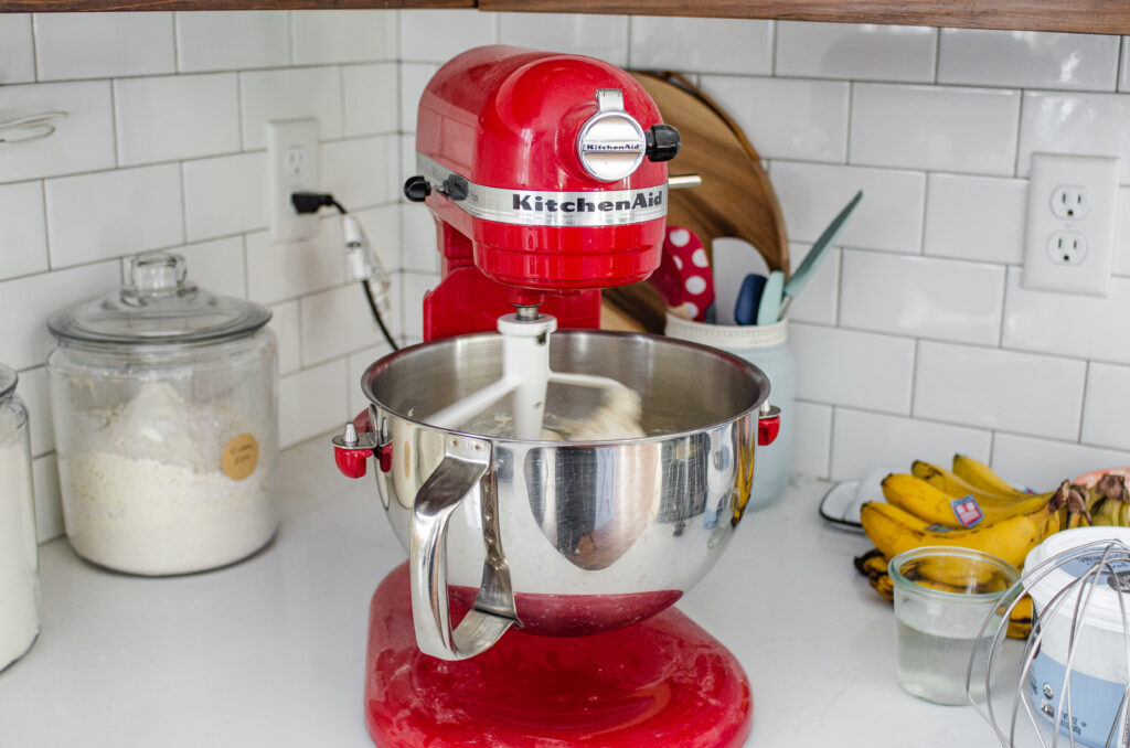 A red stand mixer on a white countertop.