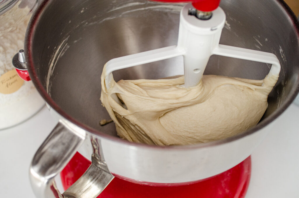 A smooth and elastic sourdough sandwich bread dough in the bowl of a stand mixer.