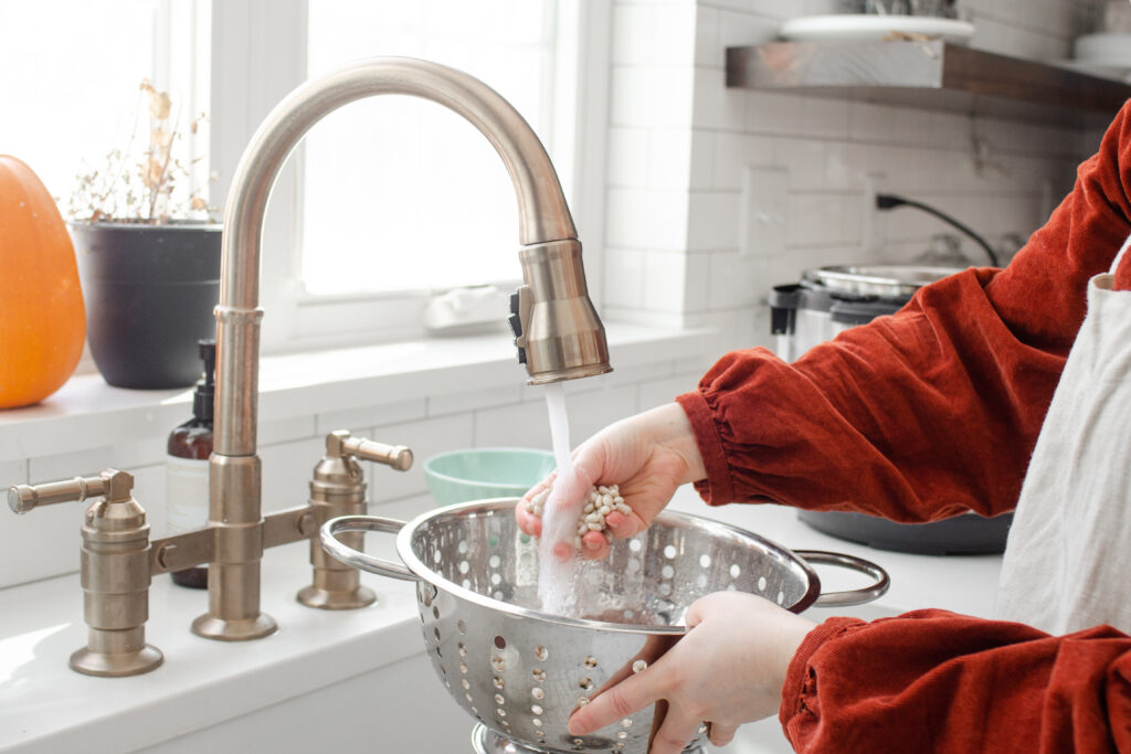 Washing beans at the sink in a colander.