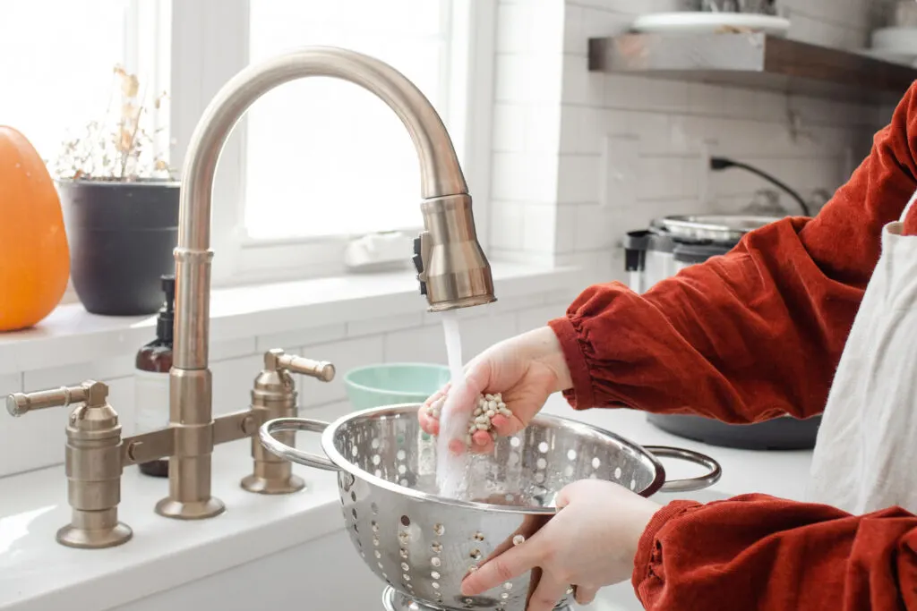 Washing beans at the sink in a colander.
