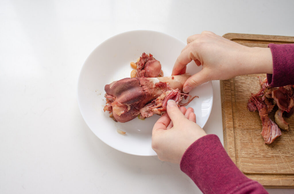 Picking the ham off of the leftover ham bone to add back to the bean soup.