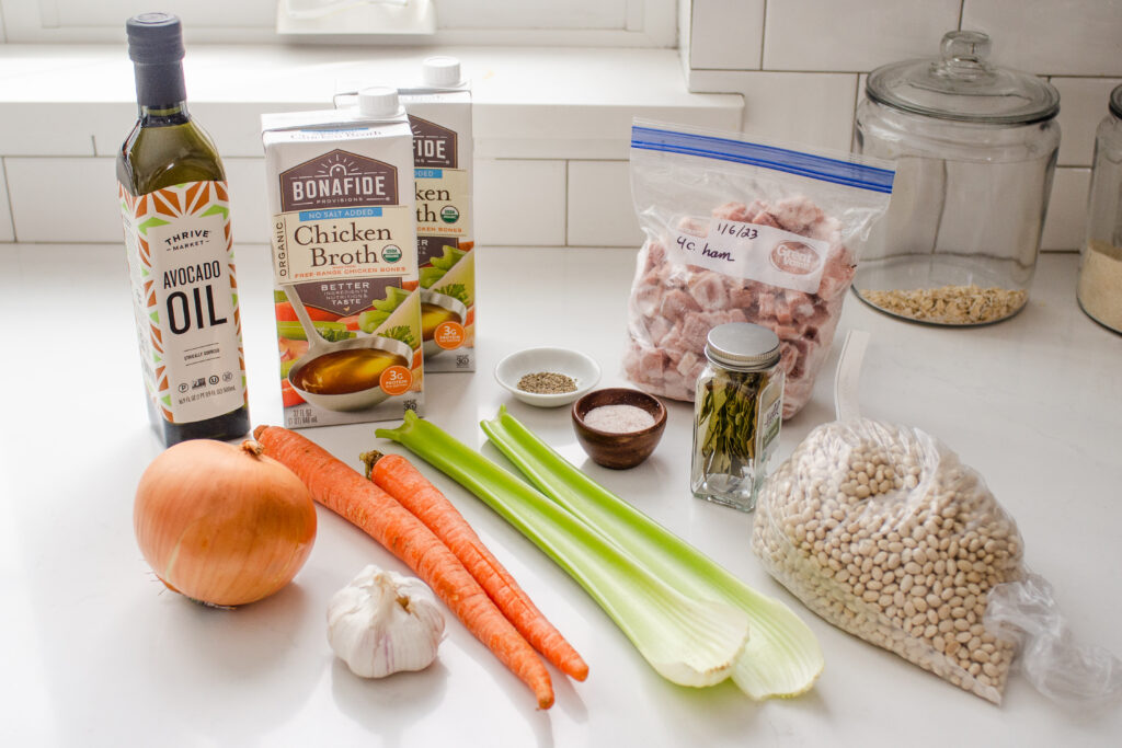 All of the ingredients needed to make ham and bean soup in the Instant Pot laid out on a white countertop with a subway tile backsplash in the background.