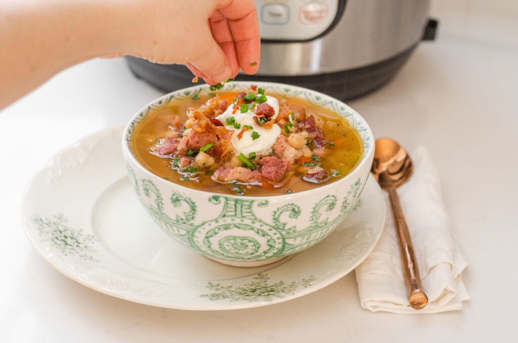 Adding sour cream, bacon, cheese, and green onions to the ham and bean soup.