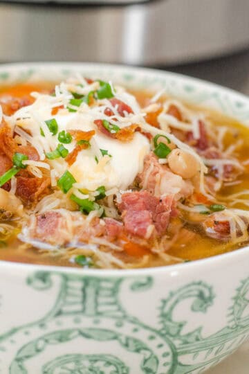 A bowl of ham and bean soup on a plate with cornbread off to the side and the Instant Pot in the background.