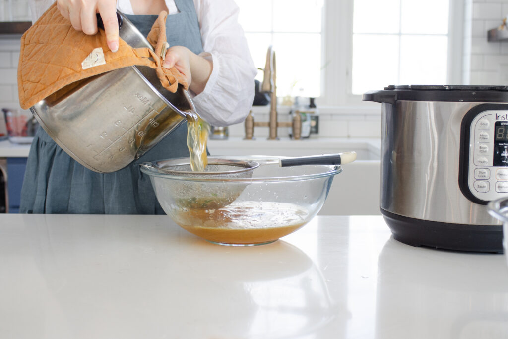 Straining the broth through a fine mesh sieve into a heat proof bowl.