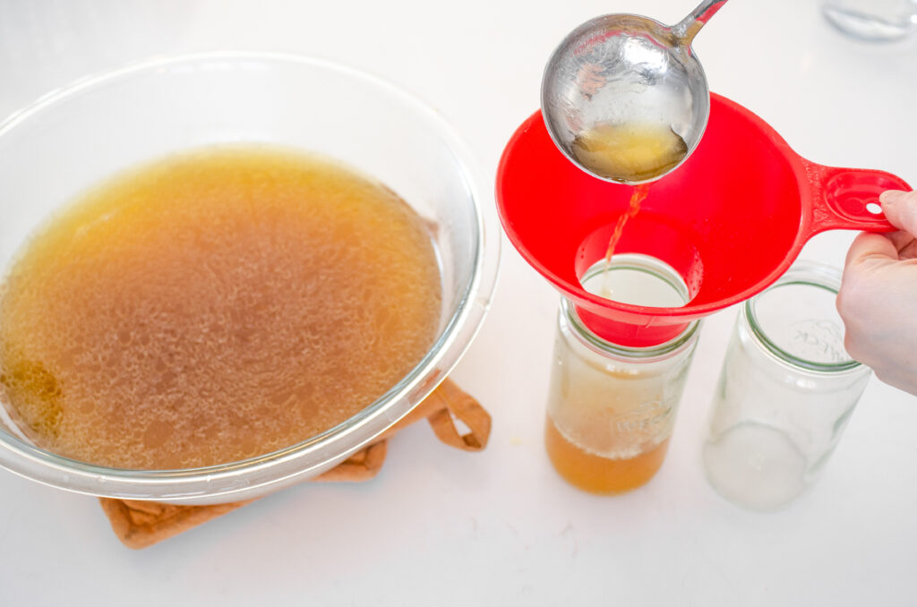 Ladling the broth in jars for storage.