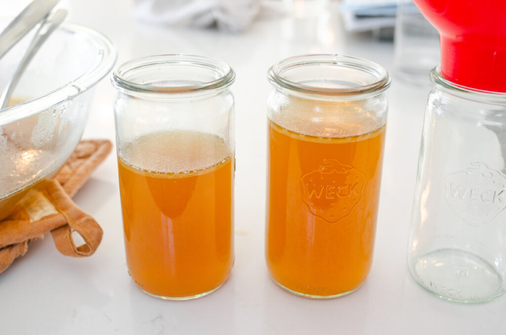 Chicken bone broth in glass Weck jars on a white countertop.