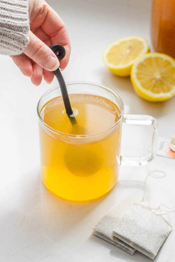 Stirring a mug of Starbucks medicine ball tea with a spoon.