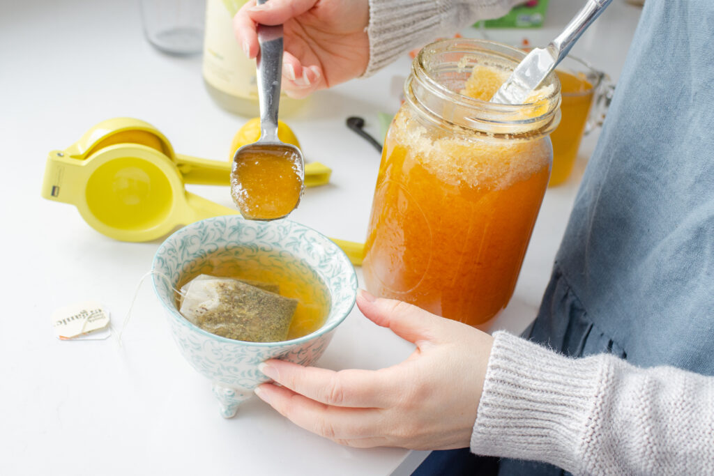 Adding lemon to the homemade medicine ball tea.