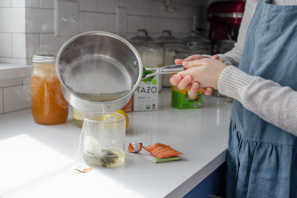 Pouring the boiling water and lemonade over the tea bags in the mug.