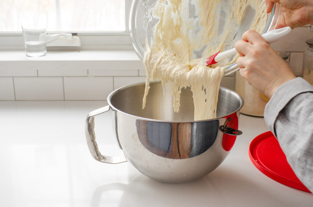 Pouring the overnight sponge into the bowl of a stand mixer.