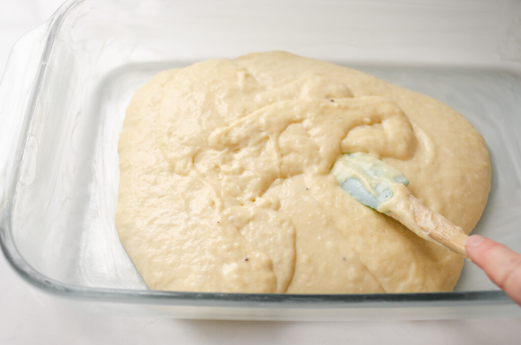 Pouring half of the sourdough coffee cake batter into the prepared pan.