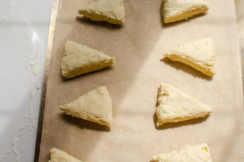 Placing the lemon scones on a parchment lined baking sheet.