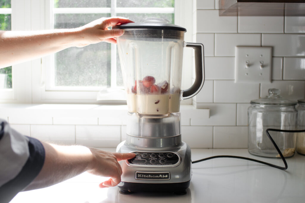 Add all of the ingredients for the strawberry milkshake to the blender pitcher.