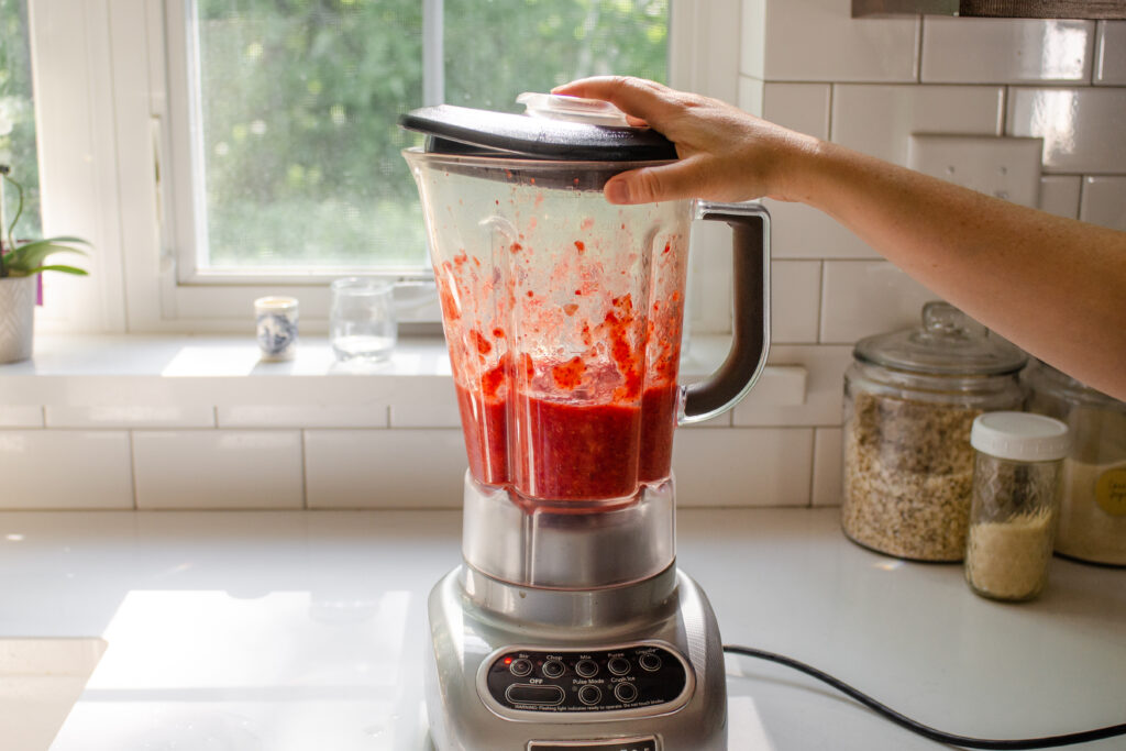 Blending strawberries in a blender to make strawberry puree. 