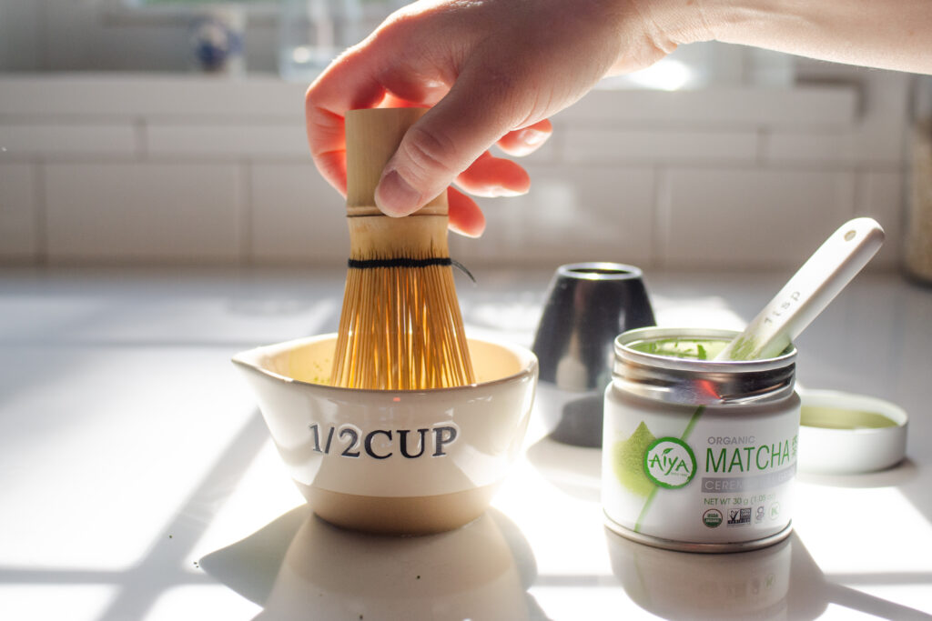 Whisking together the matcha, sugar, and water in a small bowl.