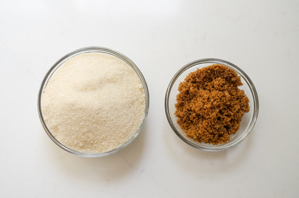 Granulated sugar and brown sugar next to each other in bowls.