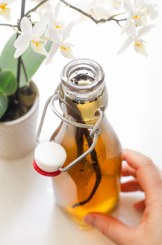 Homemade vanilla syrup for coffee in a flip top bottle next to some flowers.