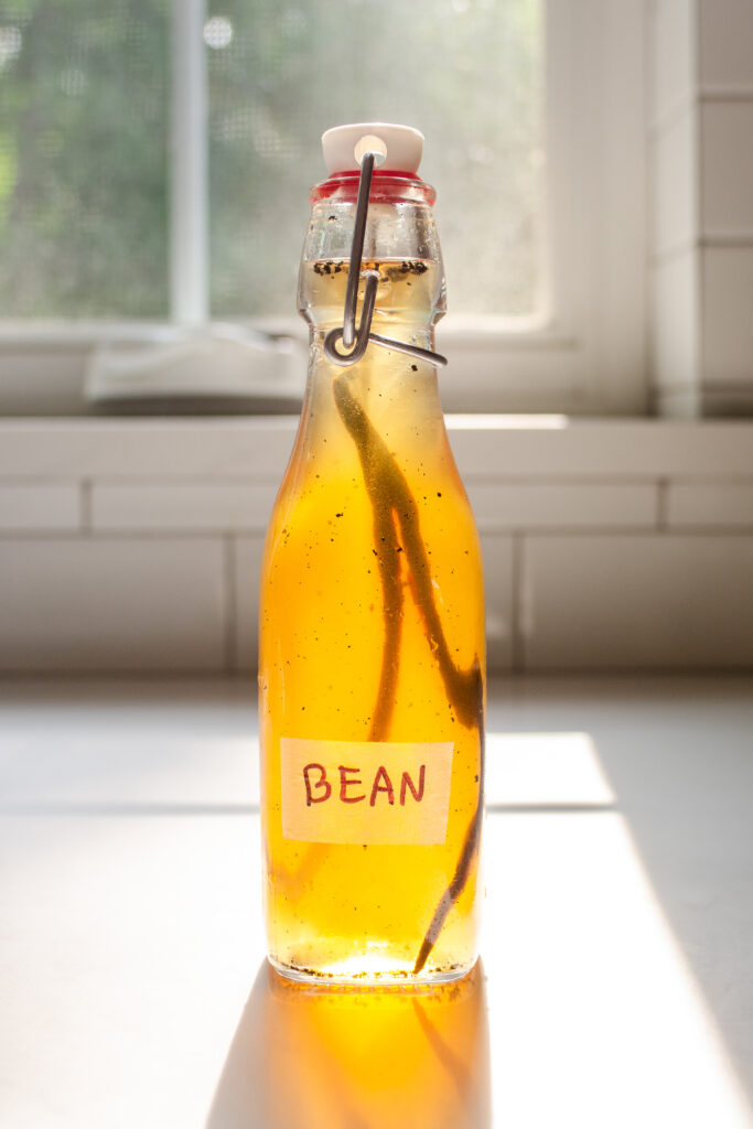 A bottle of homemade vanilla syrup for flavoring coffee on a sunny countertop.