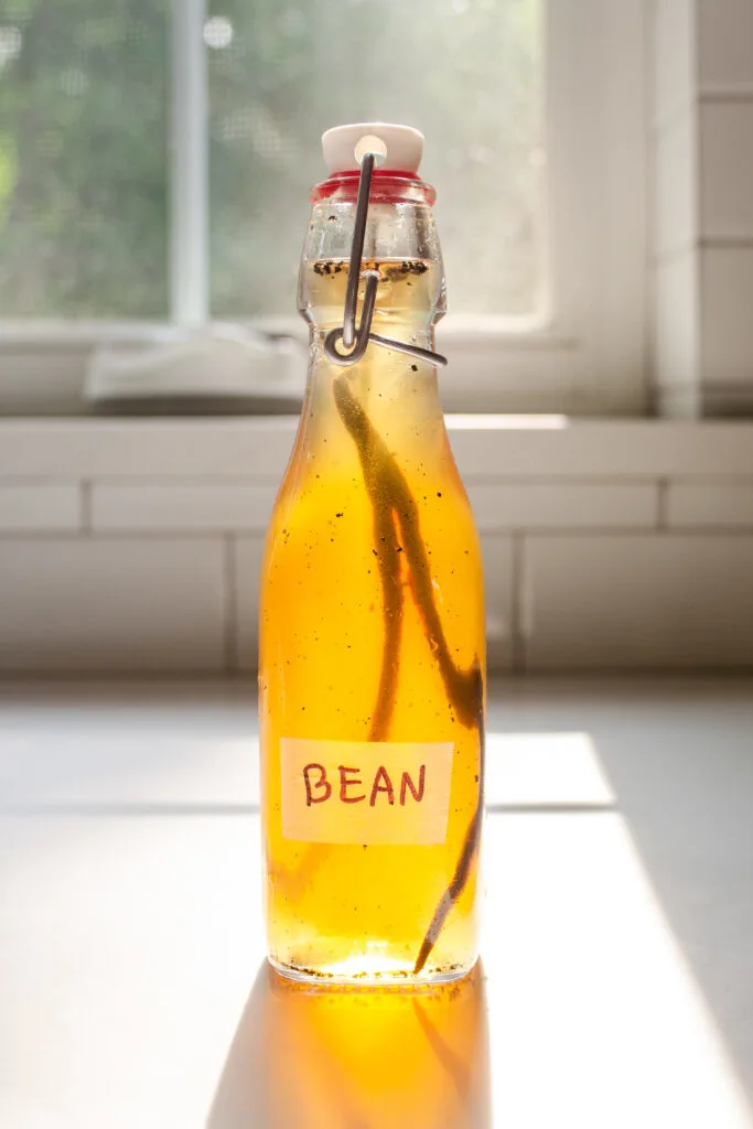 A bottle of homemade vanilla syrup for flavoring coffee on a sunny countertop.