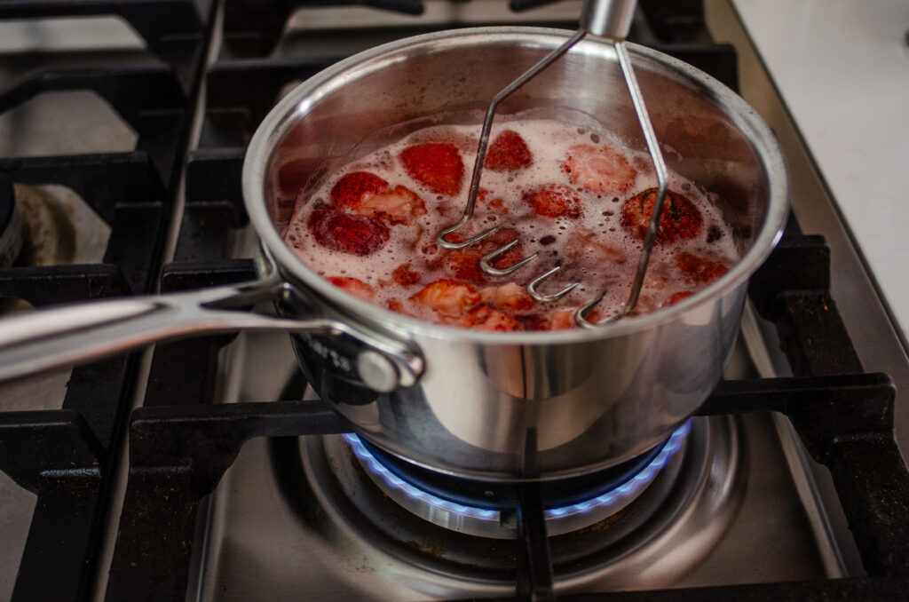 Mashing the strawberries while they cook in the water and sugar.