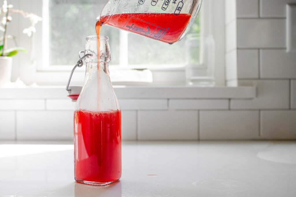 Pouring the syrup into a storage bottle.