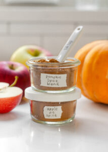 A jar of pumpkin pie spice on top of a jar of apple pie spice.