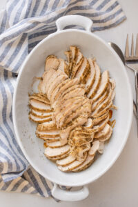 The sliced Thanksgiving chicken breasts in an oval baking dish.