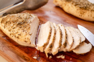 Slicing the Thanksgiving chicken breast on a wooden cutting board.