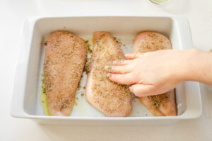 Adding the spices to the Chicken breasts.