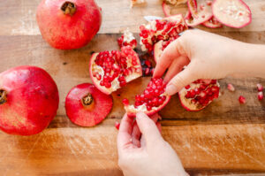 A pomegranate broken into sections on a wooden cutting board.