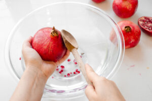 Tapping the back of a pomegranate with a wooden spoon.