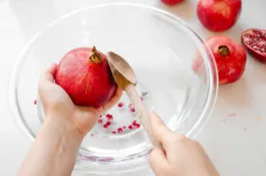 Tapping the back of a pomegranate with a wooden spoon.