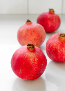 Whole pomegranates on a white countertop.