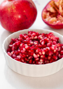 Pomegranate arils in a white ramekin.