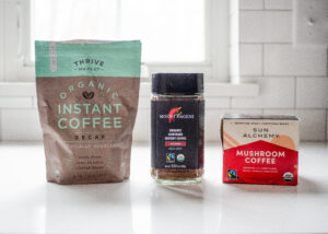 Three different brands of instant coffee on a white countertop.