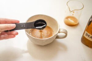 Adding vanilla syrup to instant coffee espresso in a 12 ounce stoneware mug.