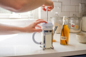 Frothing milk with a French press to pour over instant coffee espresso.