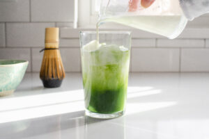 Pouring the milk and cream on top of the matcha and ice cubes.