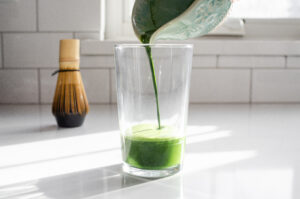 Pouring the matcha mixture into a 12 ounce glass.