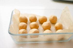 The finished peanut butter balls in a glass storage container. 