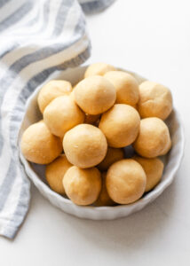 A ramekin filled with no bake peanut butter balls (without chocolate) with a striped linen napkin off to the side.