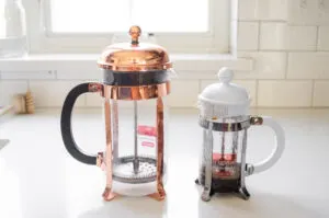 2 sizes of French presses next to each other on a white countertop.