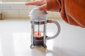 Plunging down the French press after it has been allowed to sit for 4 minutes.