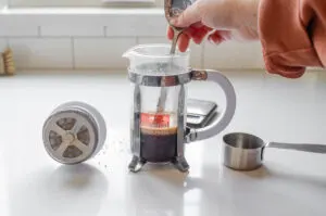 Stirring the coffee and water together with the handle of a spoon.
