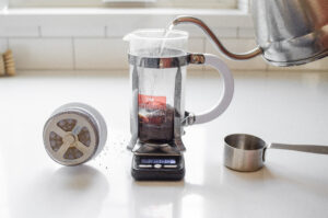 Adding hot water to the ground coffee in the French press. 