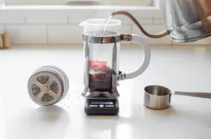 Adding hot water to the ground coffee in the French press. 