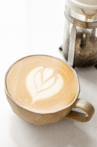 A stoneware mug with a latte with latte art.